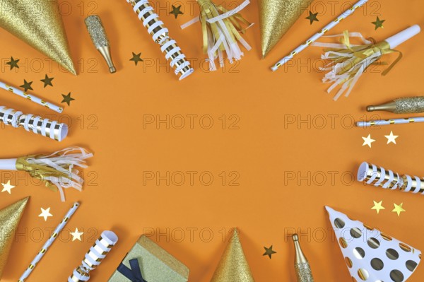 Party objects like paper hats, confetti, golden champagne bottles and star confetti forming frame