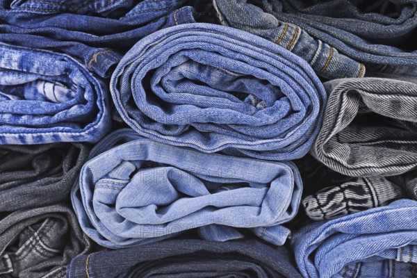 Different colored jeans pants rolled up in pile