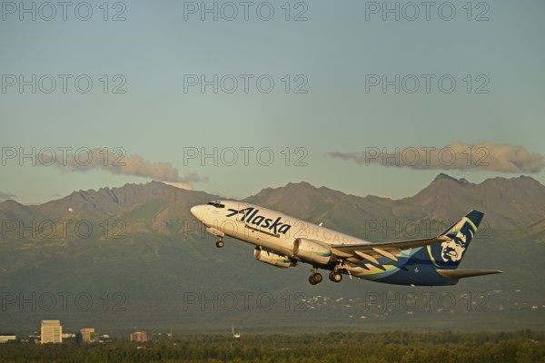 Against the backdrop of the Chugach Mountains and the houses of Anchorage, an Alaska Airlines cargo