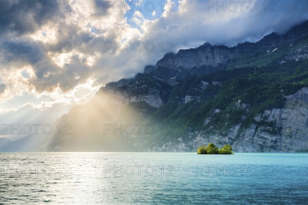 Evening sun rays on Lake Walen with chive island in the turquoise water and mountain range Schären