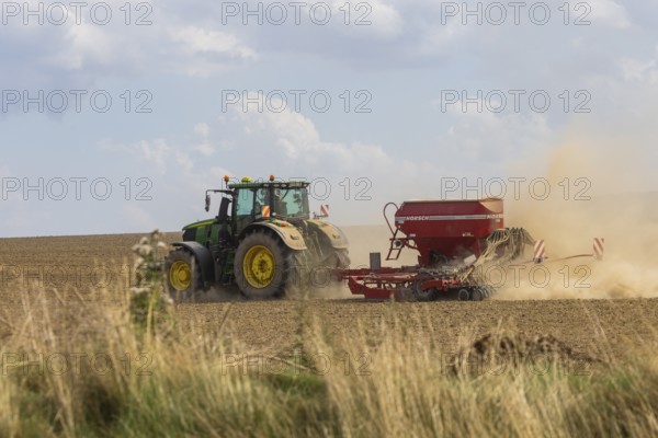 A tractor with a Horsch PRONTO DC 6 seed drill sowing in a dry field in late summer., Doma, Saxony,