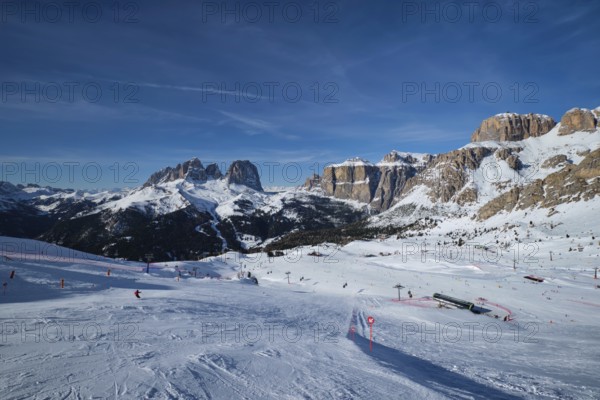 View of a ski resort piste with people skiing in Dolomites in Italy. Ski area Belvedere. Canazei,
