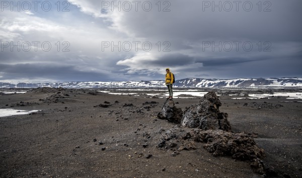 Hikers in snow-covered volcanic landscape with volcanic sand and petrified lava, crater of Askja