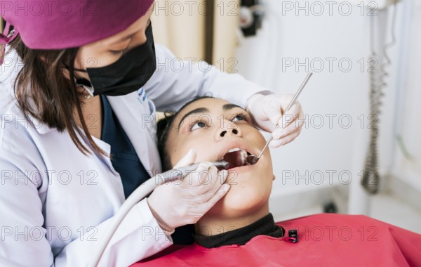 Female dentist cleaning and examining a female patient mouth. Dental specialist cleaning the teeth