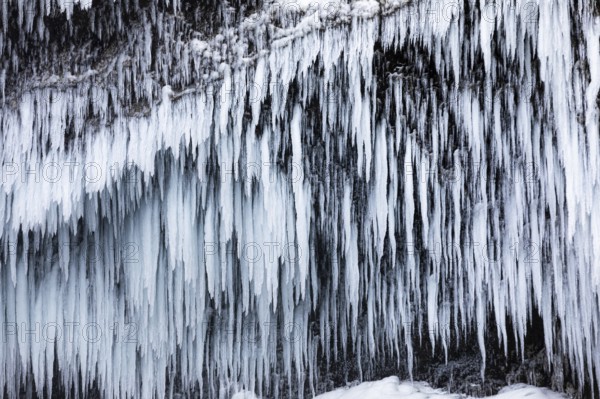 Icicles on the rock face at Skogafoss waterfall, Sudurland, Iceland, Europe