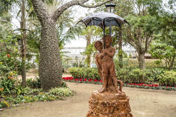 Fountain Fuente de los Niños del Paraguaswith two children under an umbrella in Parque Genovés,