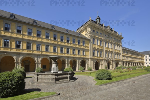 Inner courtyard and fountain with baroque princely building with arcade and gardens of the