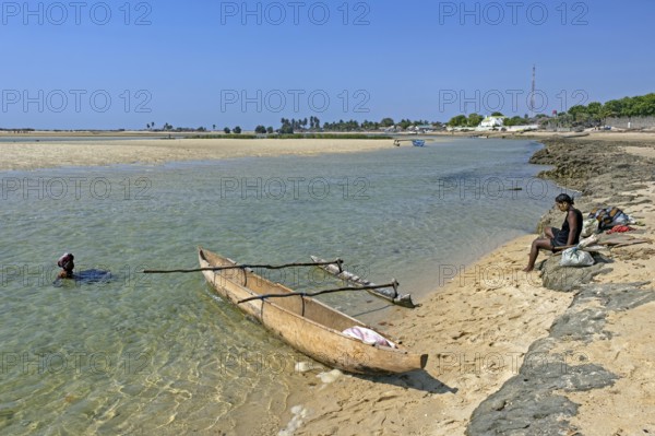 Single-outrigger canoe and two local Malagasy women on the beach at the coastal village Belo sur