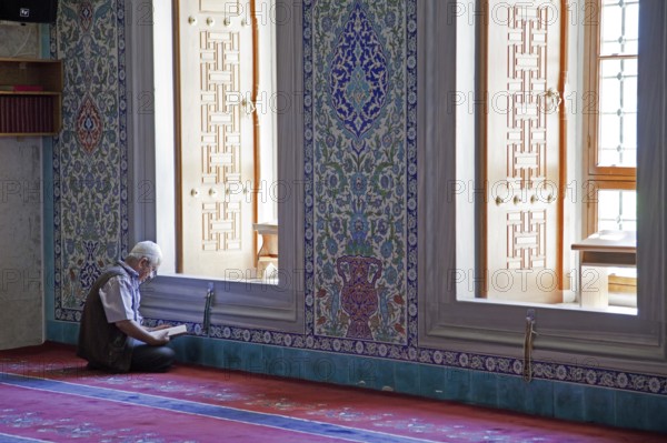 Turkish man reading the Koran in the Kocatepe Camii, largest mosque in Ankara, Turkey, Asia