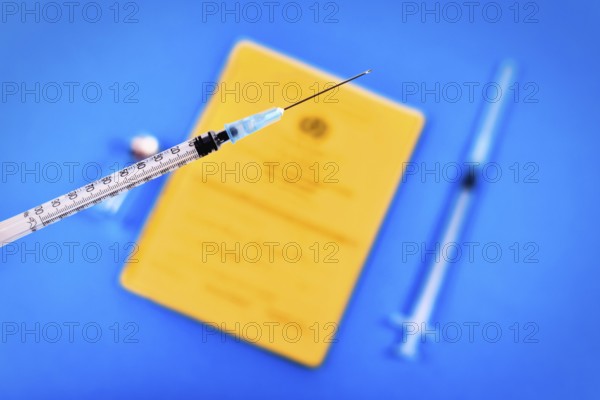 Vaccine concept with syringe in front of blurry vial and yellow international certificate of