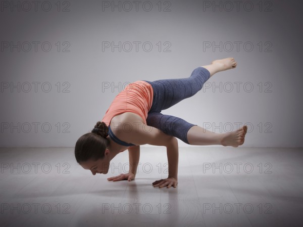 Beautiful sporty fit yogini woman practices yoga asana eka pada koundinyasana 1, pose 1 dedicated
