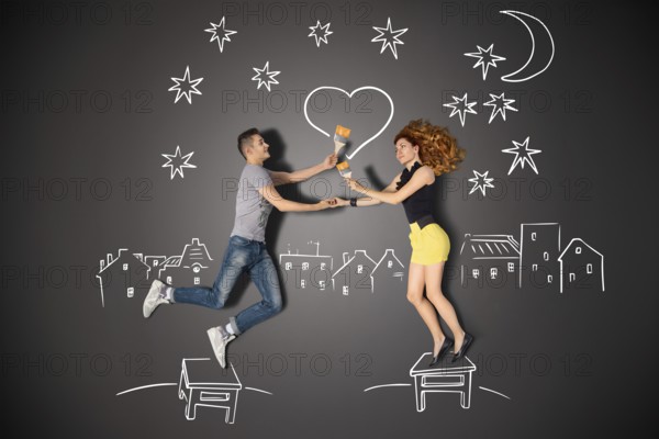 Happy valentines love story concept of a romantic couple standing on a stool and painting a heart
