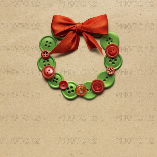 Creative concept photo of Christmas wreath made of buttons on a brown background