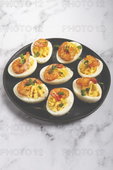 Boiled eggs stuffed with yolk and seasoned with mayonnaise, stuffed eggs with shrimp, on a black