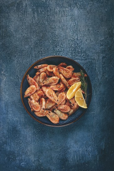 Fried shrimp, with shell and head, unpeeled, size 70-90, on a blue background, homemade, no people