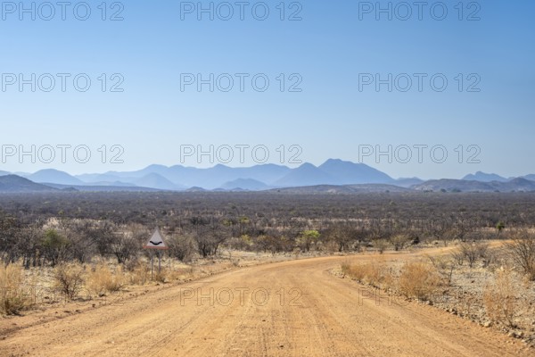 Gravel track leads through barren dry landscape with hills, Kaokoveld, Kunene, Namibia, Africa