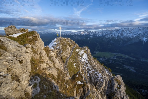 Mountaineer at the summit of the Kramerspitz with summit cross, at sunset, in autumn, Ammergau