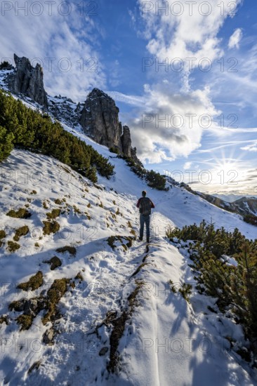 Hikers on a hiking trail with snow, sun star, ascent to Kramerspitz, in autumn, Ammergau Alps,