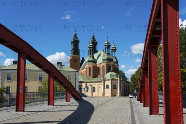 The bridge with red arches leads directly to a historic church with dominating towers, Cathedral,
