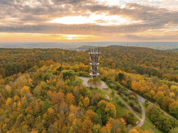 Sunlight bathes the observation tower and the surrounding autumn forest in vibrant colours,