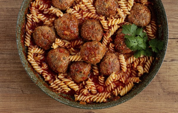 Minced meat meatballs, in tomato sauce, with fusilli pasta, in a cast-iron pan, homemade, no people