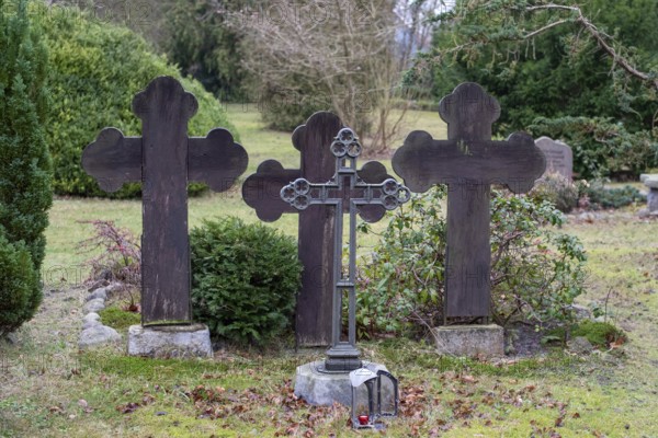 Three dark gravestones in a quiet cemetery, surrounded by bushes and bare trees, Seemannskirche