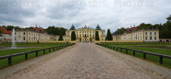 Front view of a baroque palace under a cloudy sky with a well-tended garden, Branicki Palace,