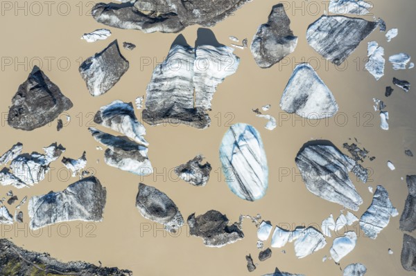 Glacier tongue of the Öræfajökull, small icebergs melting in the lagoon, muddy water, top down