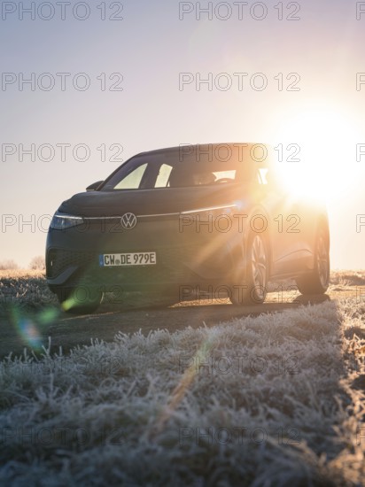 A car parked on a frosted meadow in the low sun, rays of light breaking through, car sharing,