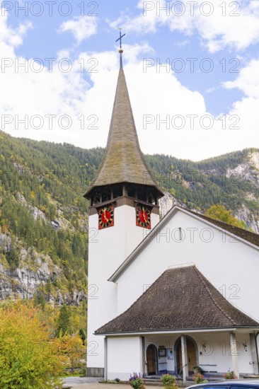 Small church with characteristic tower against an autumnal wooded mountain backdrop, Lauterbrunnen,