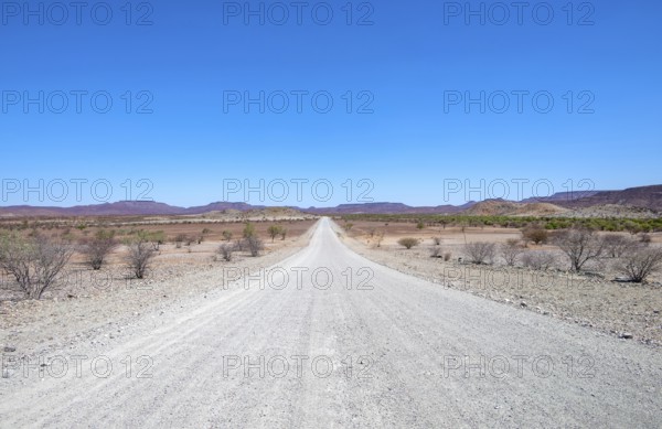 Gravel track leads through barren dry landscape with hills, Damaraland, Kunene, Namibia, Africa