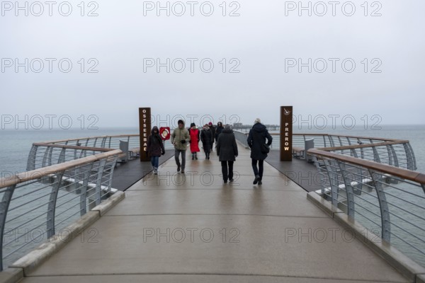 A gloomy day at a pier with several people looking towards the sea, Prerow pier,