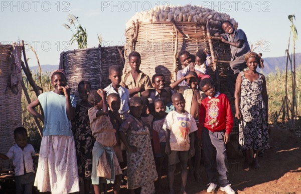 Villagers stand in front of a full maize store in a rural settlement, Malawi, southern Africa,