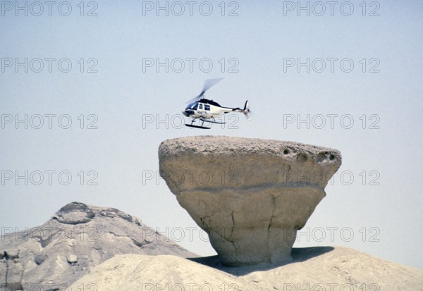 Bell 206 JetRanger helicopter landing on a rocky outcrop Arabian Desert, Saudi Arabia Oil industry