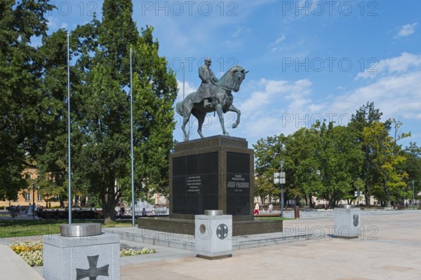 Monumental equestrian statue in a sunny park with surrounding vegetation, monument, equestrian