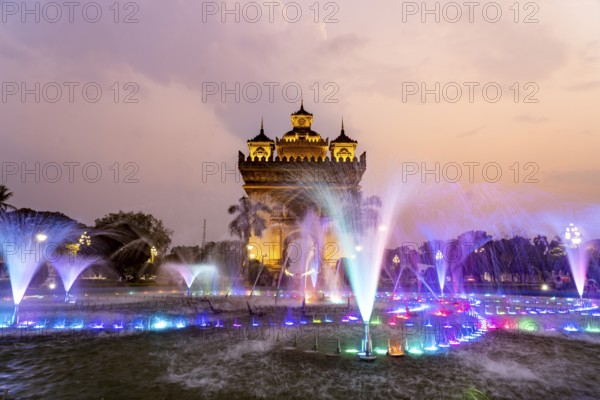 Colourfully illuminated fountain at Patuxai Victory Gate at dusk, capital Vientiane, Laos, Asia
