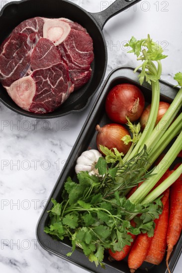 Sknuckle on the bone, raw meat for ossobuco, in a cast-iron pan, baking sheet with vegetables, top