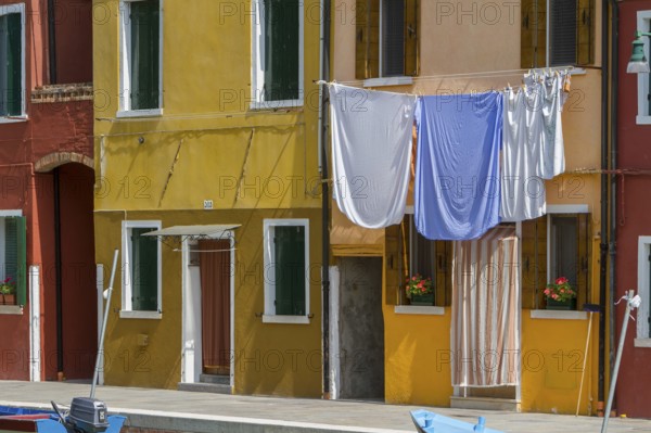 Laundry hangs on a yellow façade, the Mediterranean style creates a cosy atmosphere, Burano,