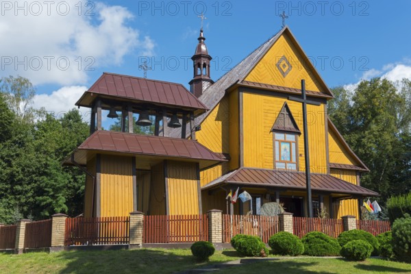 Yellow wooden church with bell tower and red roof, surrounded by trees and sky, Church of the Holy