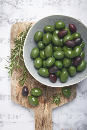 Chalkidiki olives, classic Greek green olives, in a bowl on a cutting board, top view, without