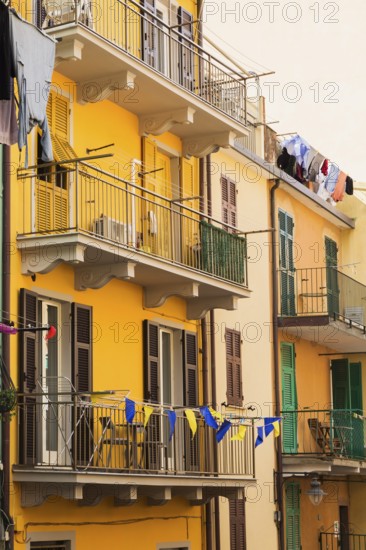 Yellow and beige stucco cladded residential apartment building facade and washed clothes drying on