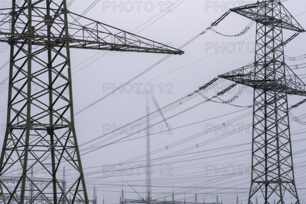 Wind farm in the fog, high-voltage pylons, dark doldrums, no wind no direct sunlight, in the