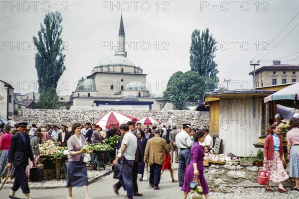 People shopping at street market with Gazi Husrev-beg mosque minaret in background, Sarajevo,