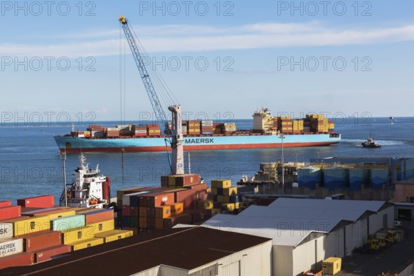 Maersk Serangoon cargo ship loaded with metal box shipping containers being guided by pilot boats