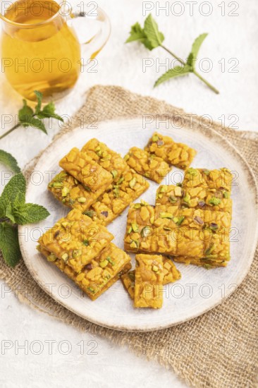 Traditional iranian dessert sohan with glass of green tea on a gray concrete background and linen