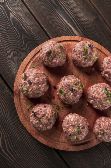 Raw meatballs, with micro greenery, on a cutting board, homemade, rustic, no people