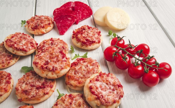 Mini pizzas, salami with mozzarella cheese, on a white table, top view, no people