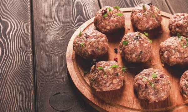 Raw meatballs, with micro greenery, on a cutting board, homemade, rustic, no people
