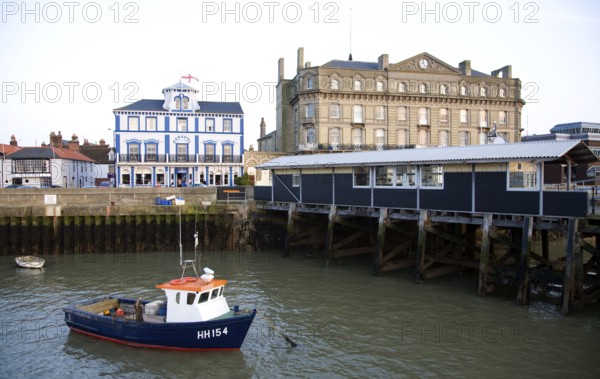 Fishing boat in harbour, Harwich, Essex, England, UK with Pier Hotel and Former Great Eastern Hotel