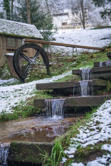 A small water wheel with a snow-covered stream in picturesque winter, spa garden, Bad Wildbad,